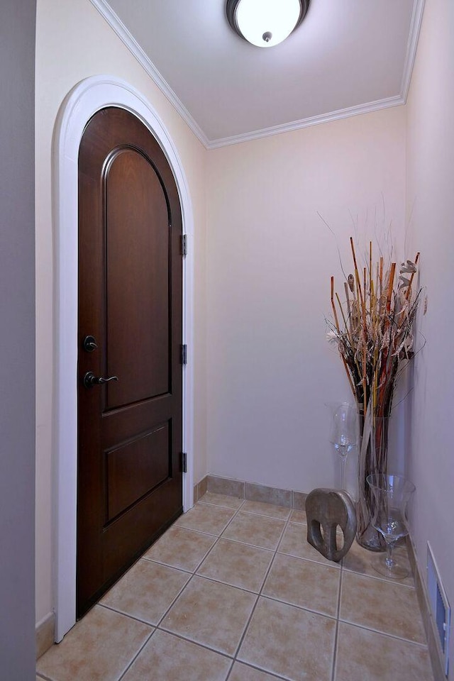 foyer with arched walkways, crown molding, and light tile patterned floors
