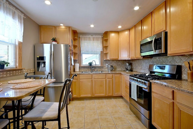 kitchen featuring appliances with stainless steel finishes, a sink, open shelves, light stone countertops, and backsplash