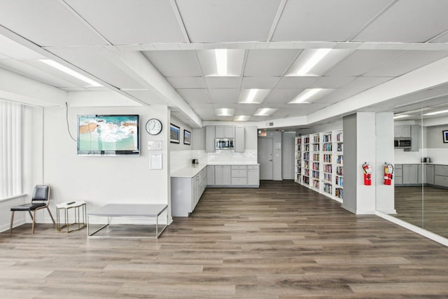 misc room with baseboards, a drop ceiling, and wood finished floors