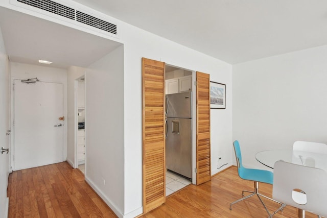 corridor featuring baseboards, visible vents, and light wood-type flooring