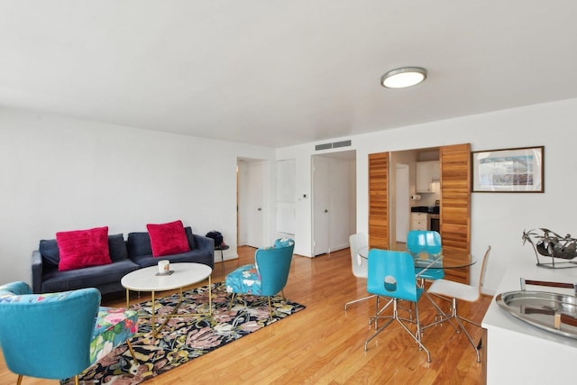 living area featuring light wood-style flooring and visible vents