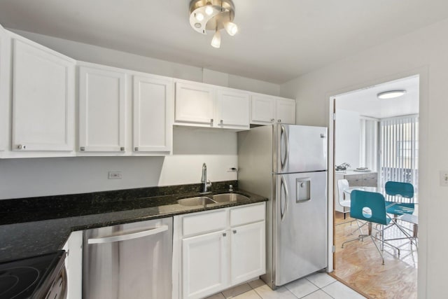kitchen featuring white cabinets, appliances with stainless steel finishes, a sink, and dark stone counters