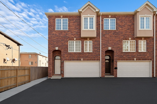 multi unit property with driveway, fence, brick siding, and an attached garage