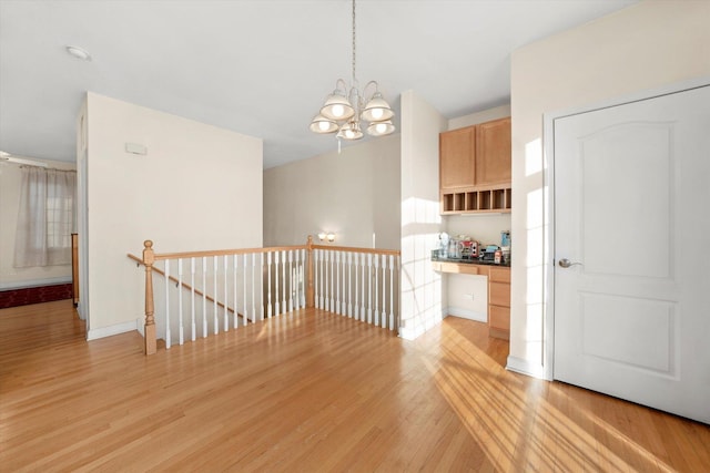 interior space featuring an upstairs landing, a chandelier, light wood finished floors, and baseboards