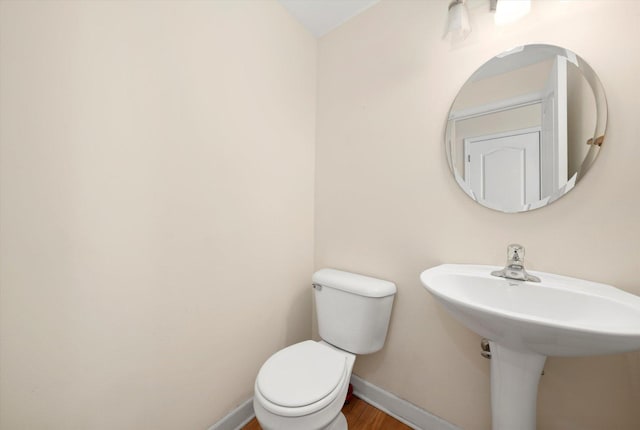 bathroom featuring toilet, a sink, wood finished floors, and baseboards
