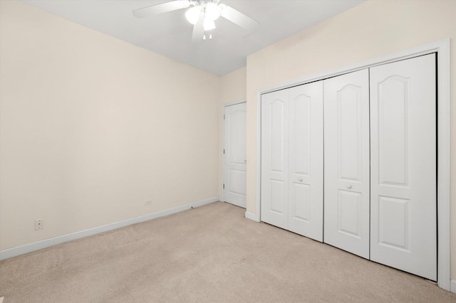 unfurnished bedroom with baseboards, a ceiling fan, light carpet, and a closet