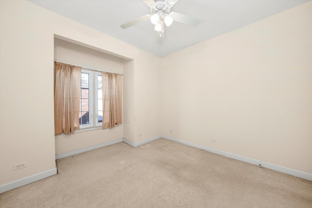 empty room with light colored carpet, visible vents, a ceiling fan, and baseboards