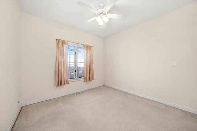 spare room with ceiling fan, light carpet, visible vents, and baseboards
