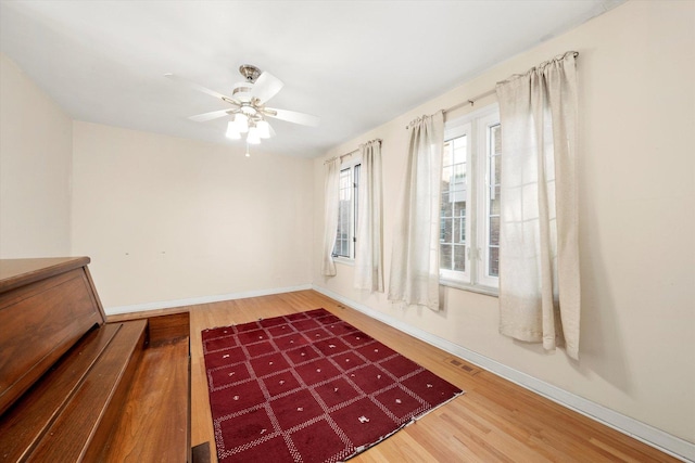 interior space with wood finished floors, ceiling fan, visible vents, and baseboards