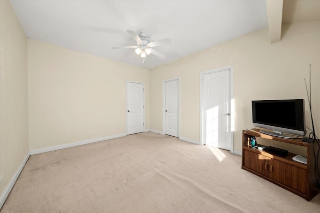 unfurnished living room with a ceiling fan, beam ceiling, carpet floors, and baseboards