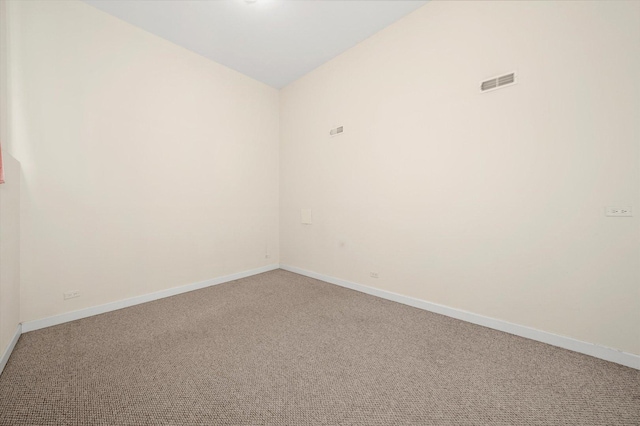 empty room featuring baseboards, visible vents, light carpet, and vaulted ceiling