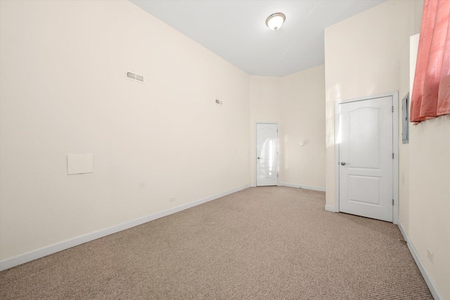unfurnished room featuring baseboards, visible vents, and light carpet