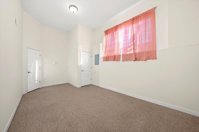 spare room with carpet flooring, electric panel, and baseboards