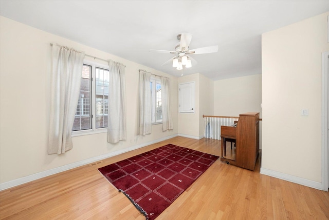 interior space with wood finished floors, a ceiling fan, and baseboards