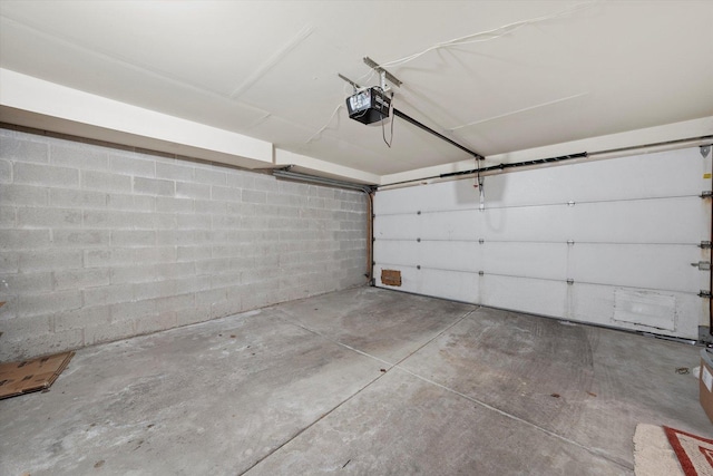 garage with a garage door opener and concrete block wall