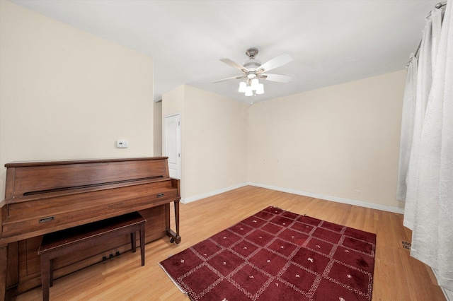 interior space with baseboards, wood finished floors, and ceiling fan