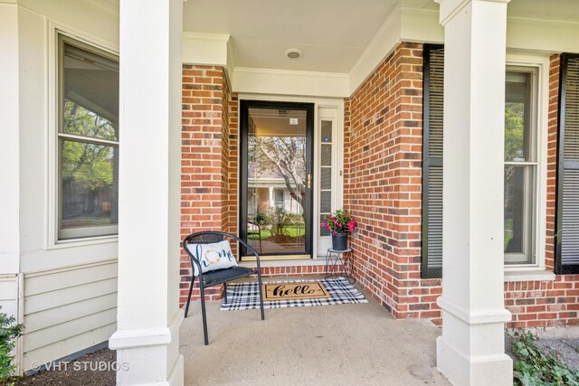 doorway to property featuring covered porch and brick siding