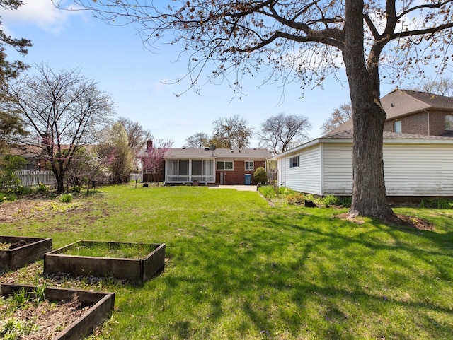 view of yard featuring a garden and a sunroom