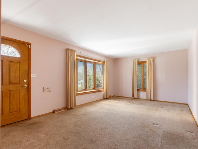 entryway featuring a healthy amount of sunlight, baseboards, visible vents, and carpet flooring