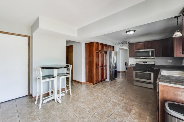1214 Lone Oak Trl, Aurora, IL 60506 - kitchen featuring appliances with stainless steel finishes, arched walkways, a sink, light tile patterned flooring, and dark countertops
