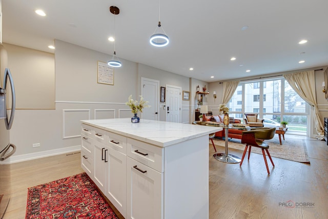 kitchen featuring recessed lighting, light stone countertops, a kitchen island, light wood-style flooring, and white cabinetry