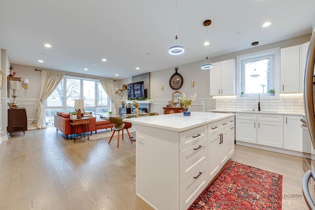 kitchen with recessed lighting, light wood-style floors, backsplash, a sink, and white cabinetry