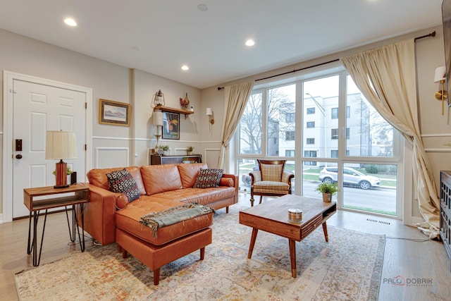 living room featuring visible vents, recessed lighting, light wood-style floors, and a decorative wall