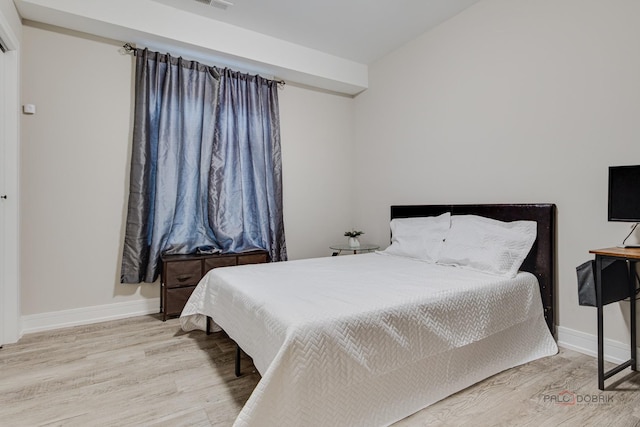 bedroom with visible vents, wood finished floors, and baseboards