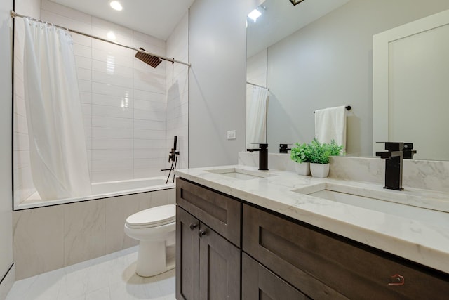 full bathroom featuring toilet, double vanity, a sink, and tiled shower / bath