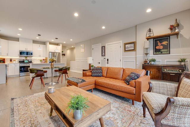 living area featuring recessed lighting, a wainscoted wall, light wood-type flooring, and a decorative wall
