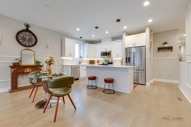 kitchen featuring decorative backsplash, white cabinets, appliances with stainless steel finishes, visible vents, and light wood-type flooring