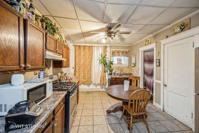 2534 S Christiana Ave, Chicago, IL 60623 - kitchen with white microwave, a drop ceiling, under cabinet range hood, gas stove, and a ceiling fan