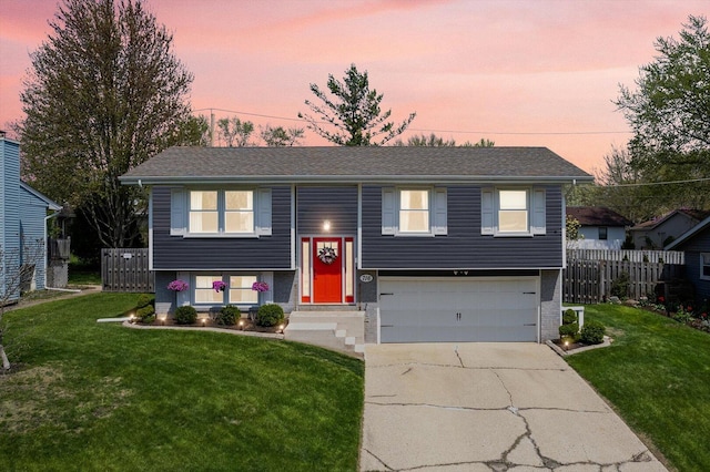 split foyer home with an attached garage, a front lawn, fence, and driveway