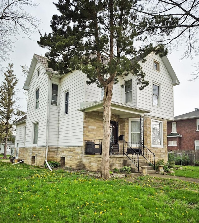 view of front of house with a front yard, fence, and stone siding