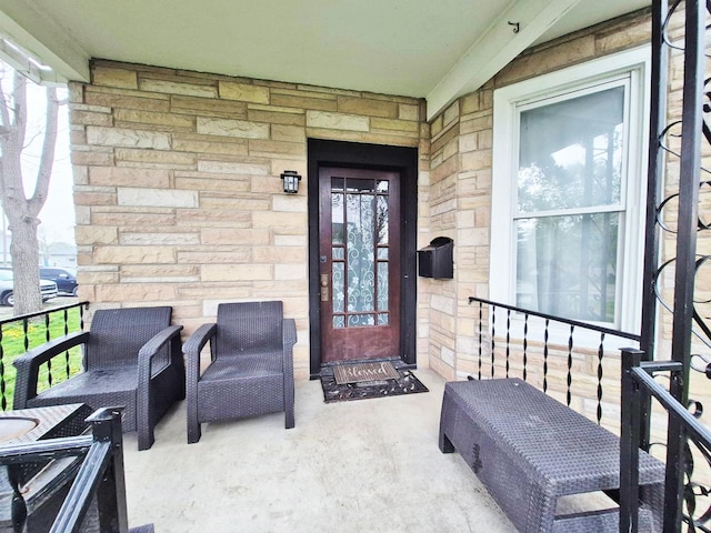 doorway to property featuring a porch and stone siding