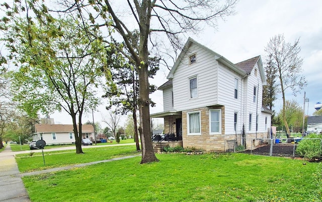 view of side of property with a lawn, fence, and stone siding