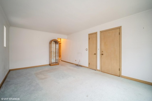 unfurnished room with light colored carpet, ornamental molding, and baseboards