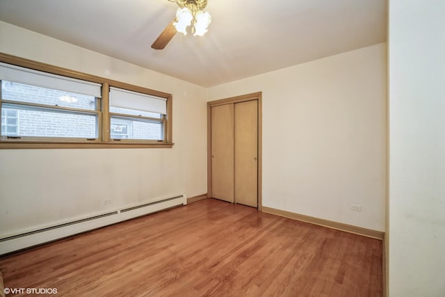 spare room with a ceiling fan, baseboards, light wood-style flooring, and a baseboard radiator