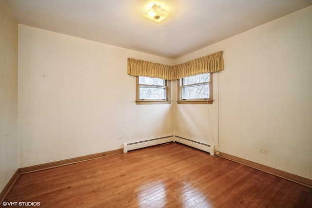 empty room featuring hardwood / wood-style flooring, baseboard heating, and baseboards