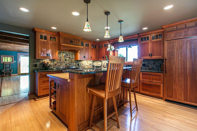 kitchen featuring light wood-style floors, glass insert cabinets, backsplash, and recessed lighting