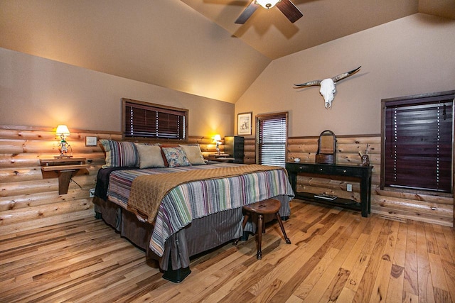 bedroom featuring log walls, ceiling fan, lofted ceiling, and hardwood / wood-style floors