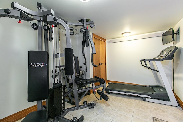 exercise area with baseboards and light tile patterned floors