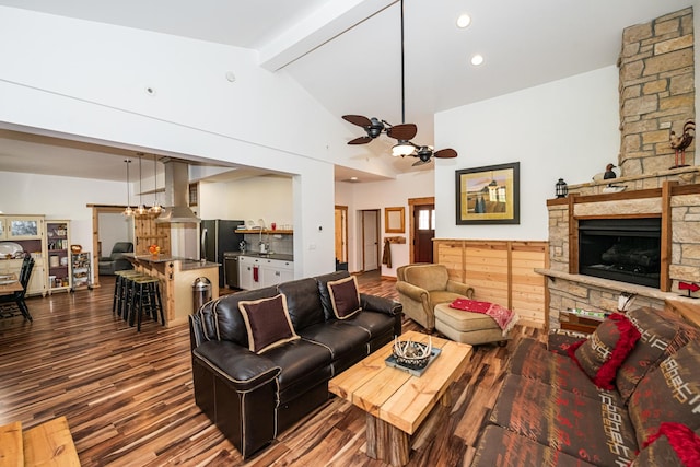 living area with dark wood-type flooring, lofted ceiling with beams, ceiling fan, and a fireplace