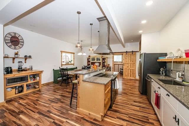 kitchen featuring open shelves, dark wood-style flooring, a barn door, a sink, and appliances with stainless steel finishes