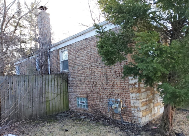 view of side of home featuring fence and brick siding