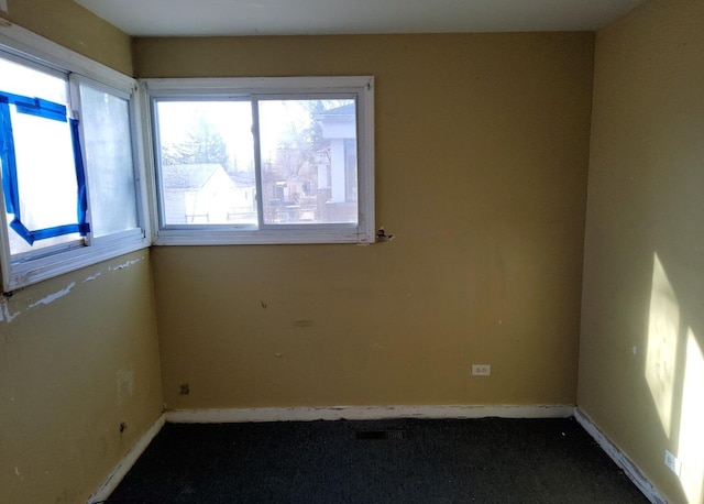 empty room with dark colored carpet and baseboards