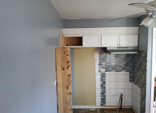 kitchen featuring white cabinets, a ceiling fan, under cabinet range hood, and decorative backsplash