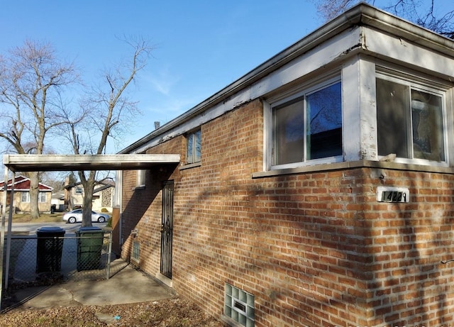 view of side of home featuring fence and brick siding