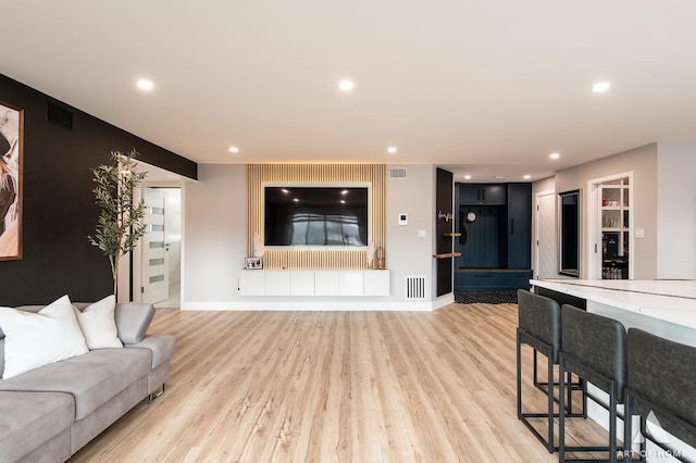 living room with baseboards, light wood-style flooring, and visible vents