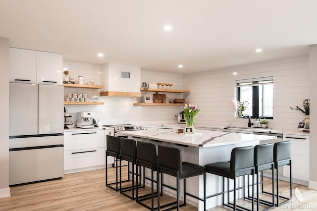 kitchen featuring open shelves, a kitchen breakfast bar, and freestanding refrigerator